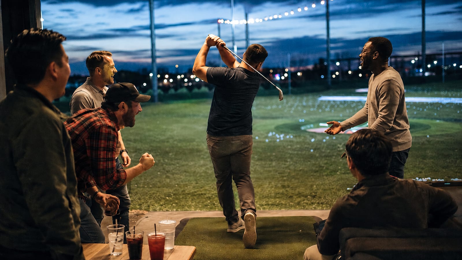 Friends cheering at a Top Golf driving range at night